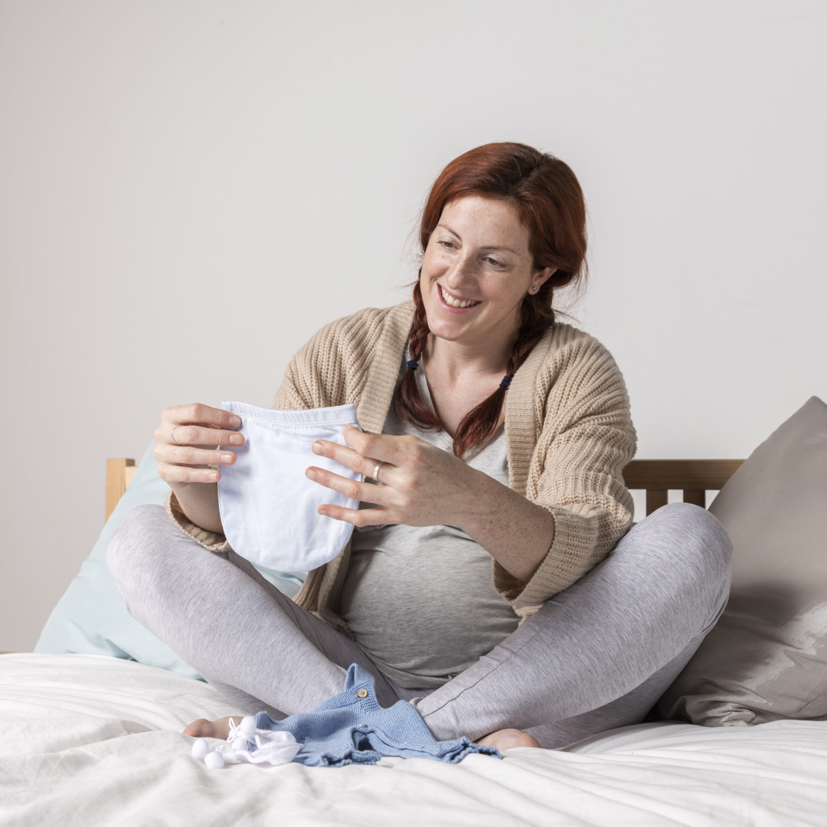 smiley-pregnant-woman-looking-baby-clothes